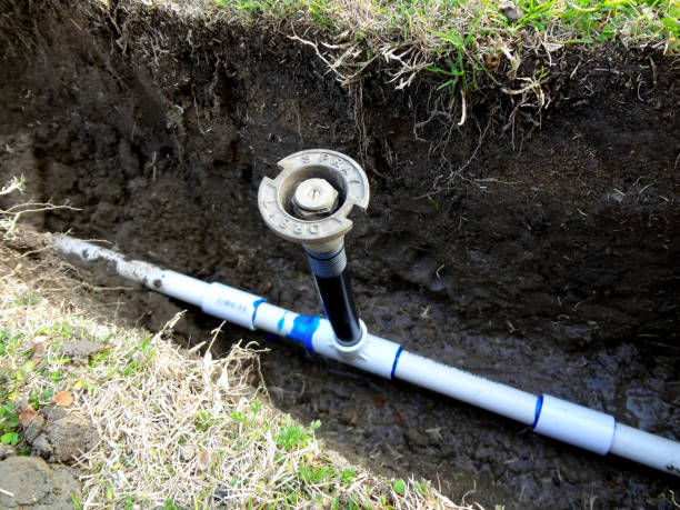 Skilled irrigation technician testing sprinkler zones and diagnosing controller wiring fault, Irrigation specialist testing sprinkler zones and adjusting spray pattern for precise lawn coverage